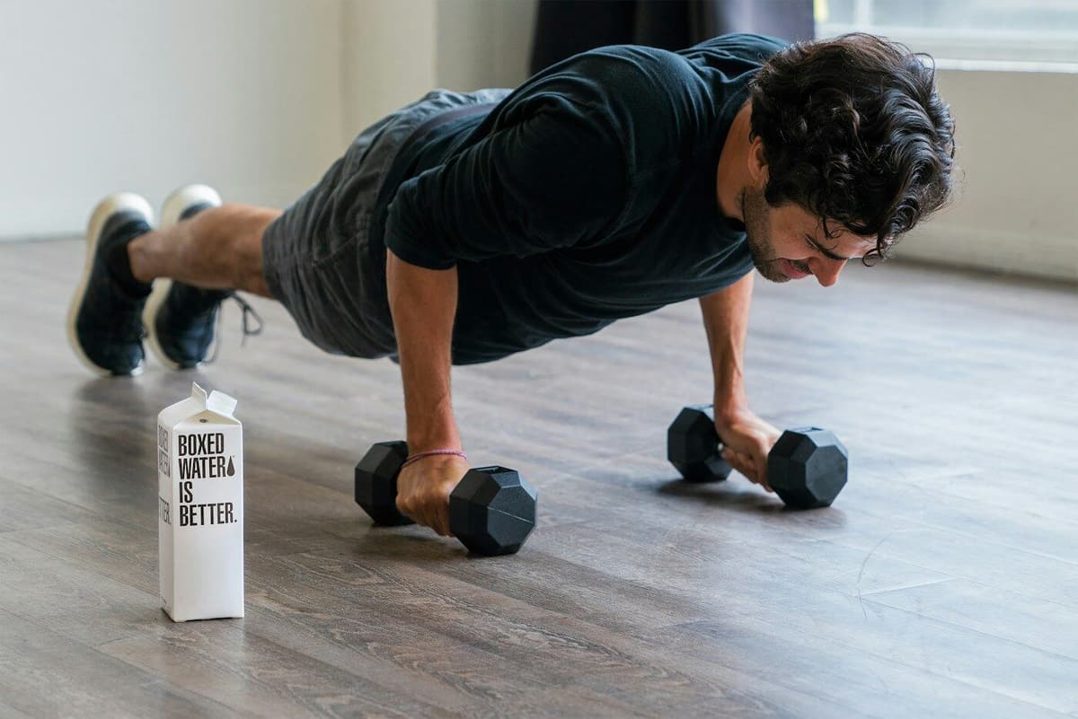 Homem a fazer flexões com halteres num studio de treino claro